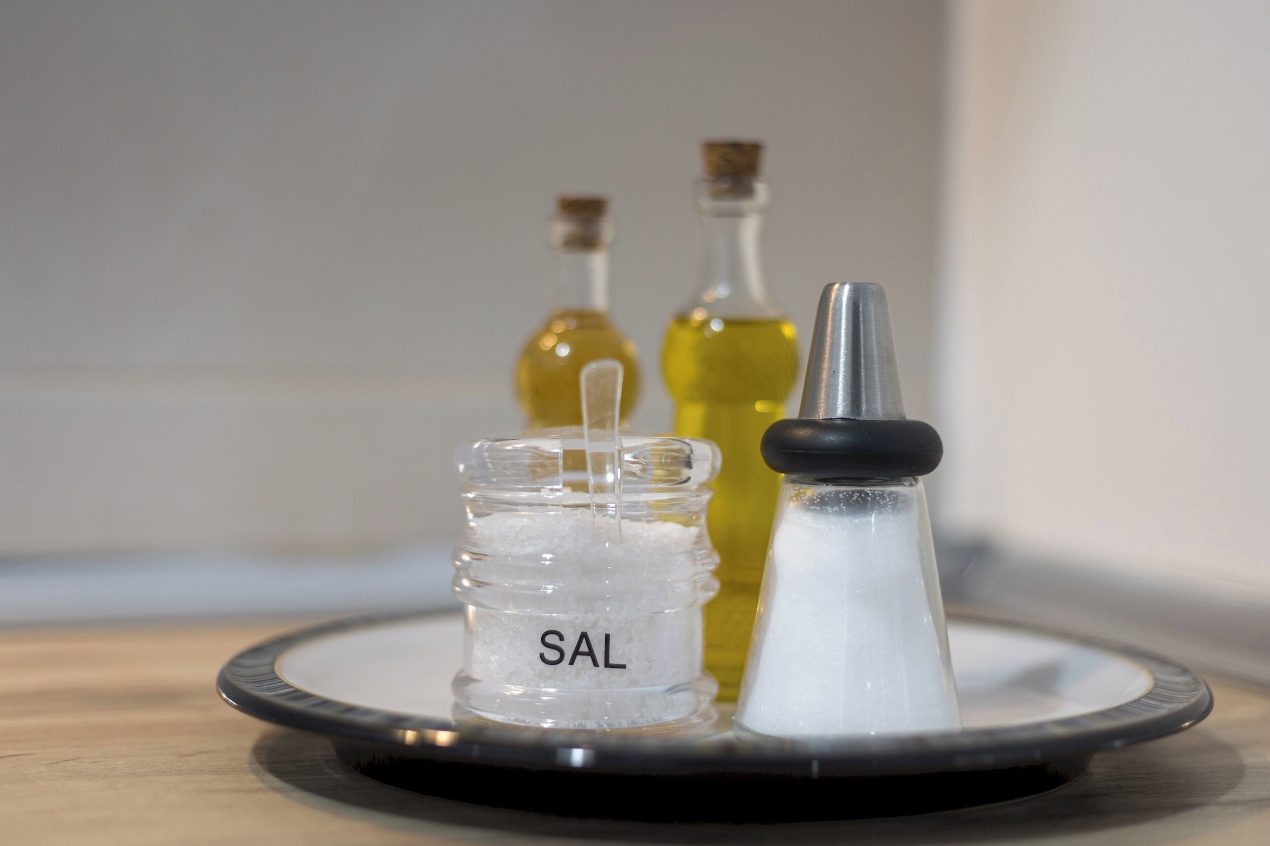 A salt shaker, a bottle of oil, and a bottle of vinegar on a tray.