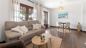 A living room with a sofa, coffee table, and dining area with chairs and a table.