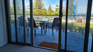 A balcony with a table and chairs, a view of parked cars, and a blue flag. - Scarborough Shores - Beachfront (Scarborough)
