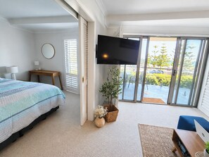 Une chambre avec un lit, une télévision, un bureau, une chaise et un balcon avec vue.