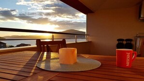A wooden deck with a table, a candle, and a red Nescafé mug. - Expansive Ciovo Apartment with Sea-Views, Balcony and Outdoor Dining - Three Bedroom Apartment (Okrug Gornji)