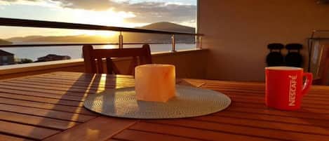A wooden deck with a table, a candle, and a red Nescafé mug.