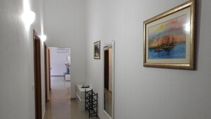 A hallway with a painting of a sailboat on the wall, a small table with a vase, and a door leading to another room. - Expansive Ciovo Apartment with Sea-Views, Balcony and Outdoor Dining - Three Bedroom Apartment (Okrug Gornji)