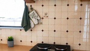 A kitchen with a black oven, a white range hood, wooden cabinets, and a tiled backsplash. - Anatolis Apartment: Near Airport, Rafina Port & Beach (Artemis)