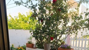A balcony with a table set for breakfast, potted plants, and a view of a building. - Anatolis Apartment: Near Airport, Rafina Port & Beach (Artemis)