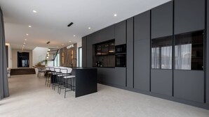 Une cuisine moderne avec des meubles de couleur sombre, un îlot central et un coin repas équipé de tabourets de bar.