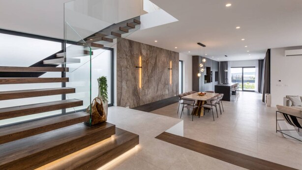 Un intérieur moderne avec un escalier en verre, un coin repas et une cuisine.
