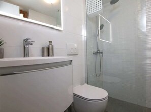 A modern bathroom with a toilet, a sink with a mirror, and a shower area. - Secluded Oasis with Pool, Outdoor Kitchen, & Landscaped Terraces - Three Bedroom Villa (Supetar)
