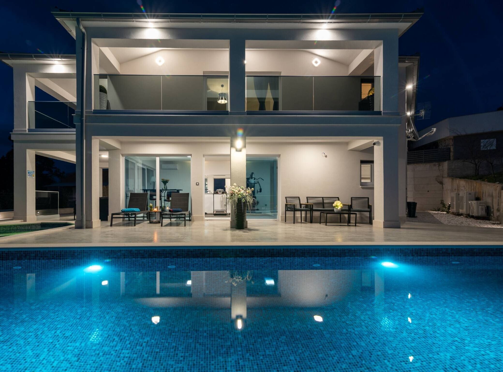 A modern two-story house with a swimming pool in the foreground.