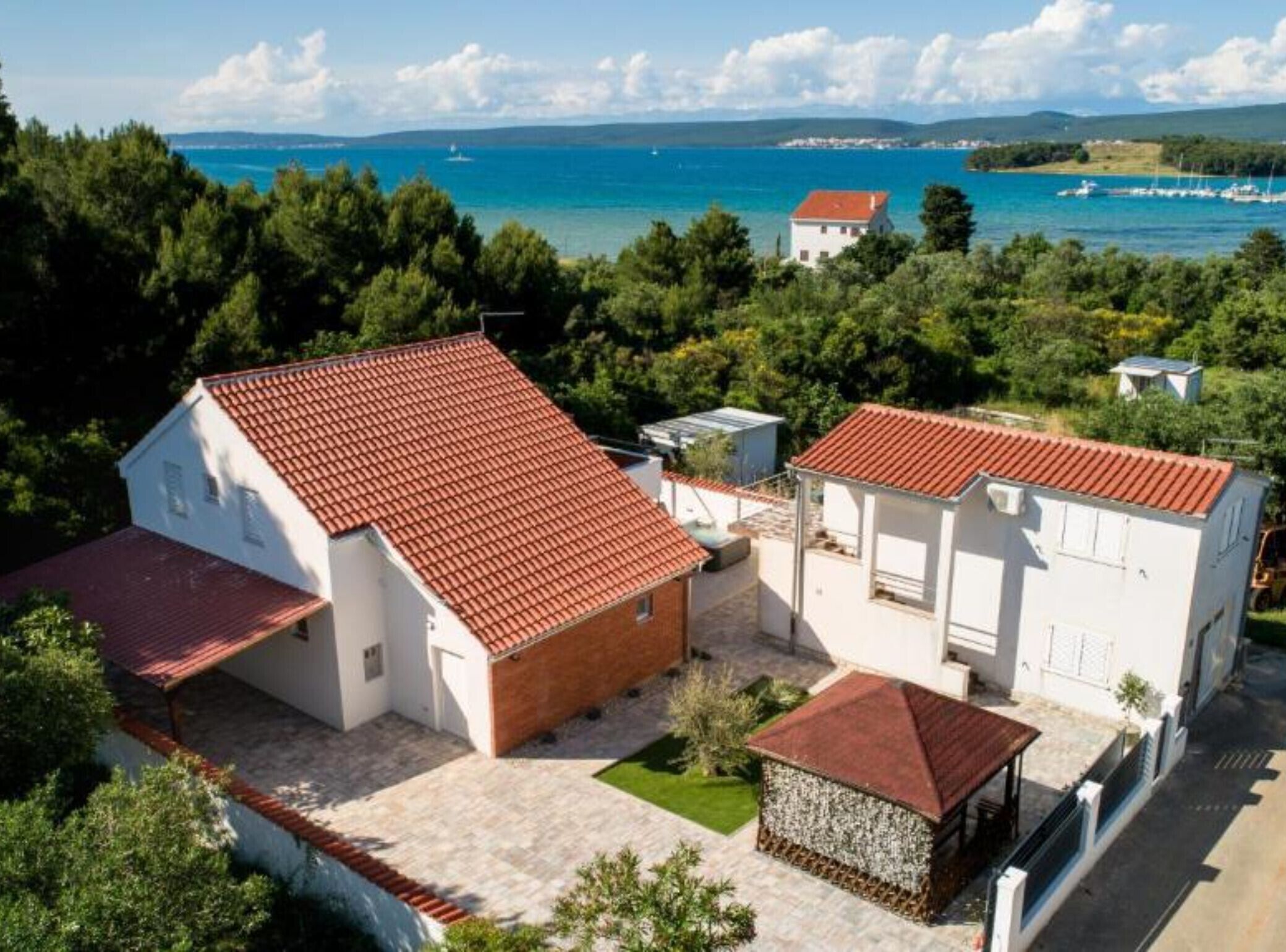 A coastal property with two white buildings, a red-tiled roof, and a view of the sea.