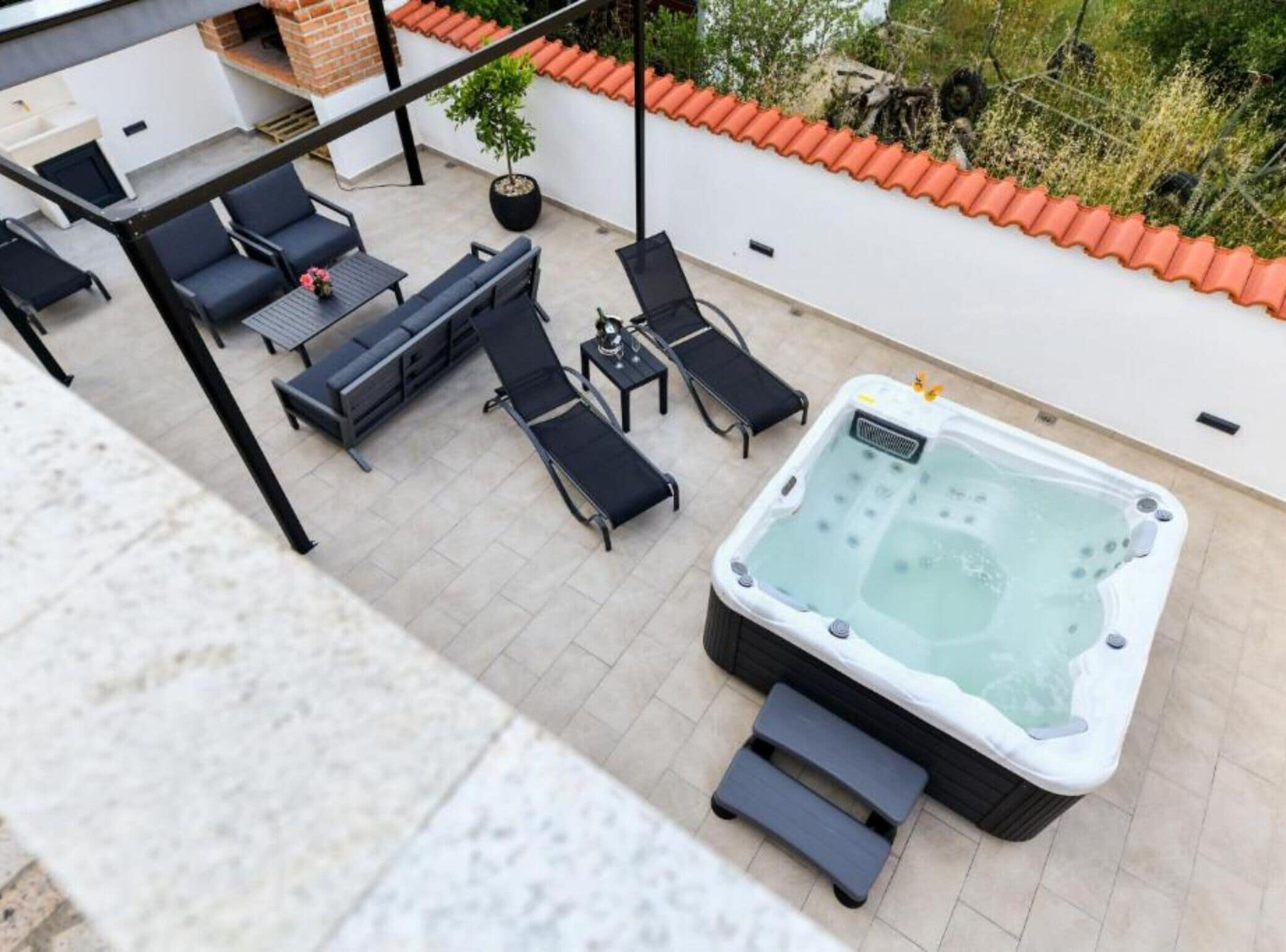 Eine Dachterrasse mit Whirlpool, Gartenmöbeln und einem Blumentopf.