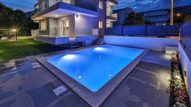 A modern two-story house with a swimming pool in the backyard.
