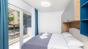 A bedroom with a bed, a wardrobe, and a balcony.