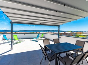 A rooftop terrace with a covered seating area, a table, and chairs. - Two Bedroom Apartment with Sea View and Balcony (Kastel Novi)