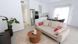 A modern living room with a beige sofa, a wooden coffee table, and a potted plant.