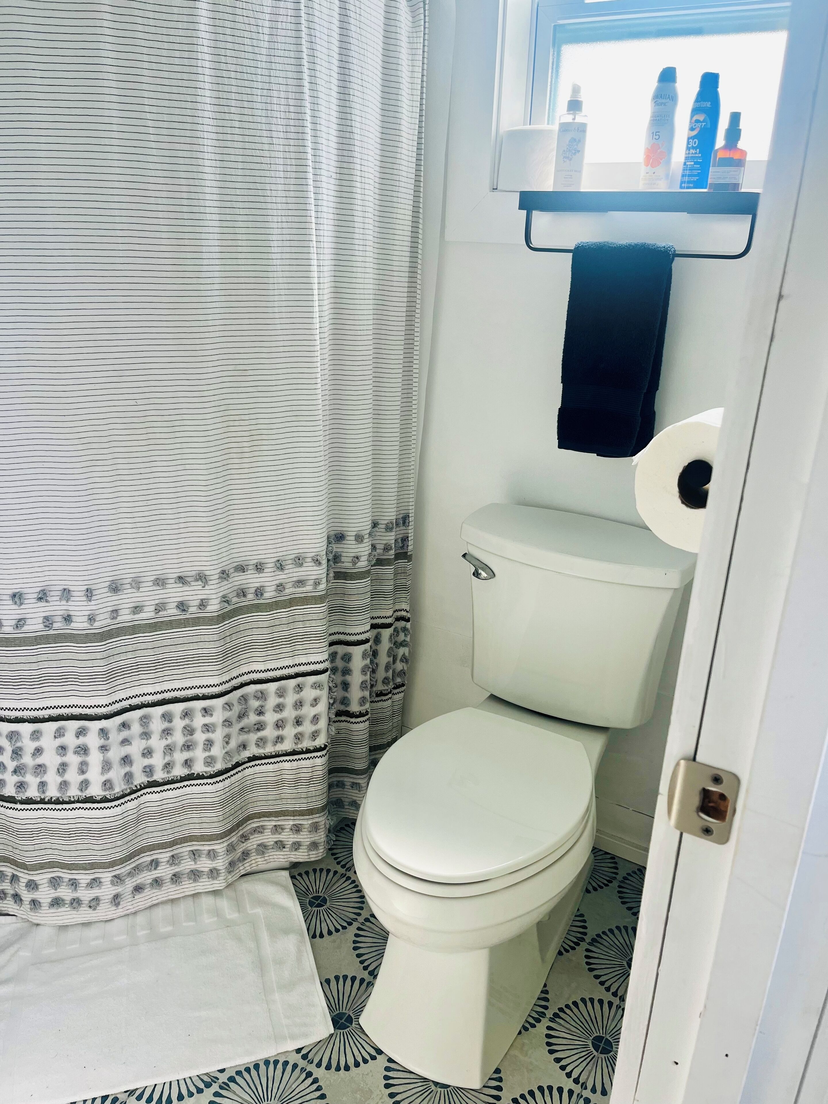 Een badkamer met een toilet, douchegordijn en een plank met toiletartikelen.