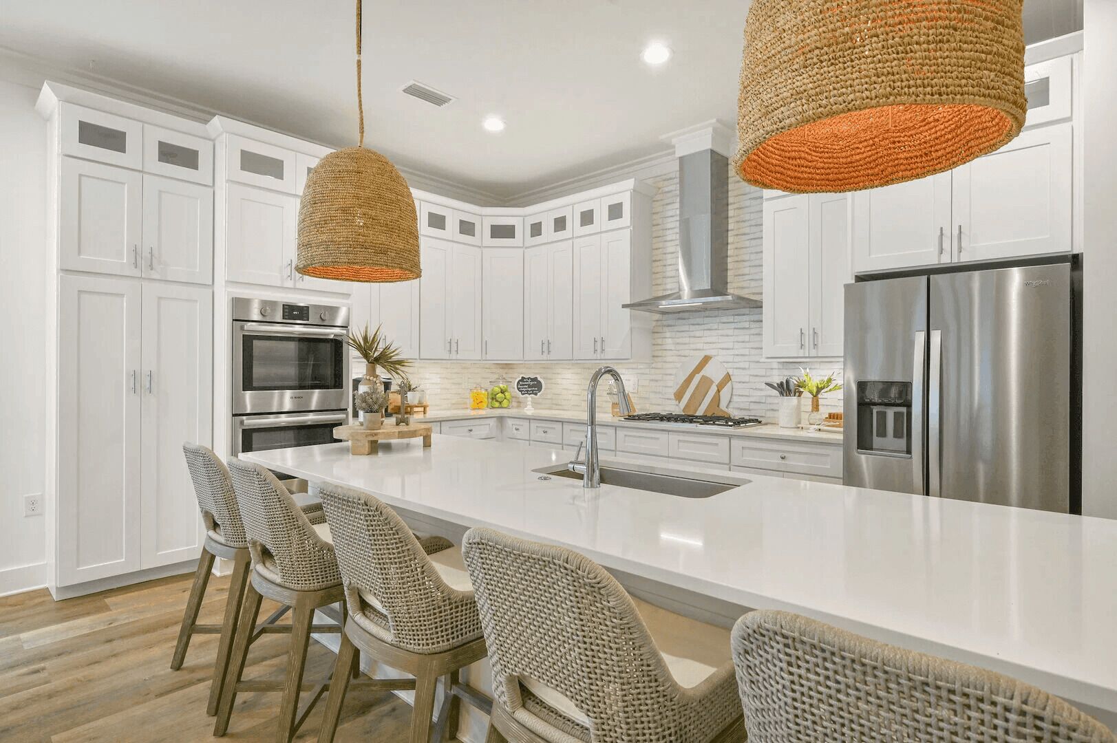 Una cocina moderna con armarios blancos, electrodomésticos de acero inoxidable y una isla grande con taburetes de bar.