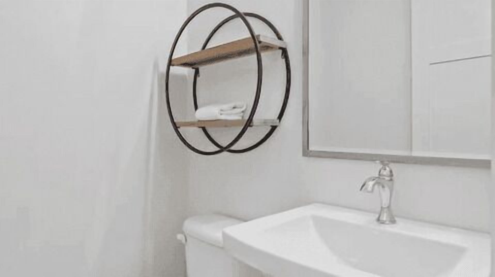 A bathroom with a white sink, a mirror, and a towel rack.