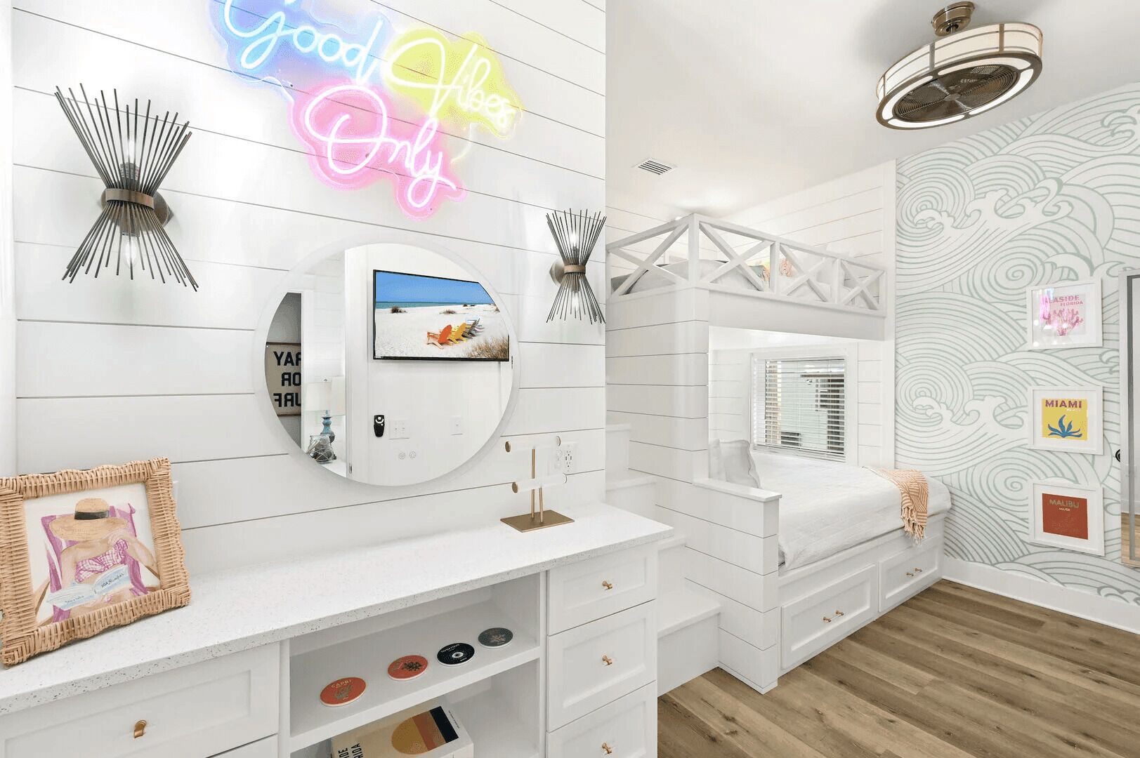 A modern bathroom with a white vanity, a round mirror, and a neon sign.