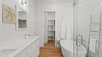 Une salle de bain moderne avec une baignoire sur pieds, une douche à parois de verre et un meuble-lavabo doté d’un grand miroir.