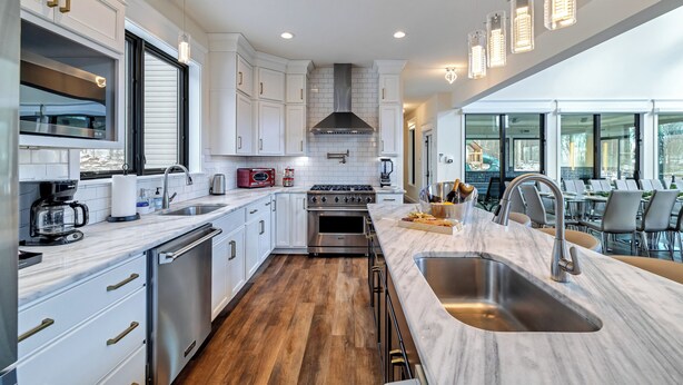 A modern kitchen with white cabinets, stainless steel appliances, and a large island with a sink. - The Perfect Pocono Escape (coolbaugh township)