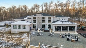 A multi-story house with a patio area featuring outdoor seating and a fire pit. - The Perfect Pocono Escape (coolbaugh township)
