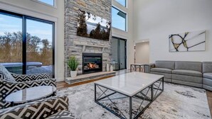 A modern living room with a stone fireplace, a gray sofa, and a coffee table. - The Perfect Pocono Escape (coolbaugh township)