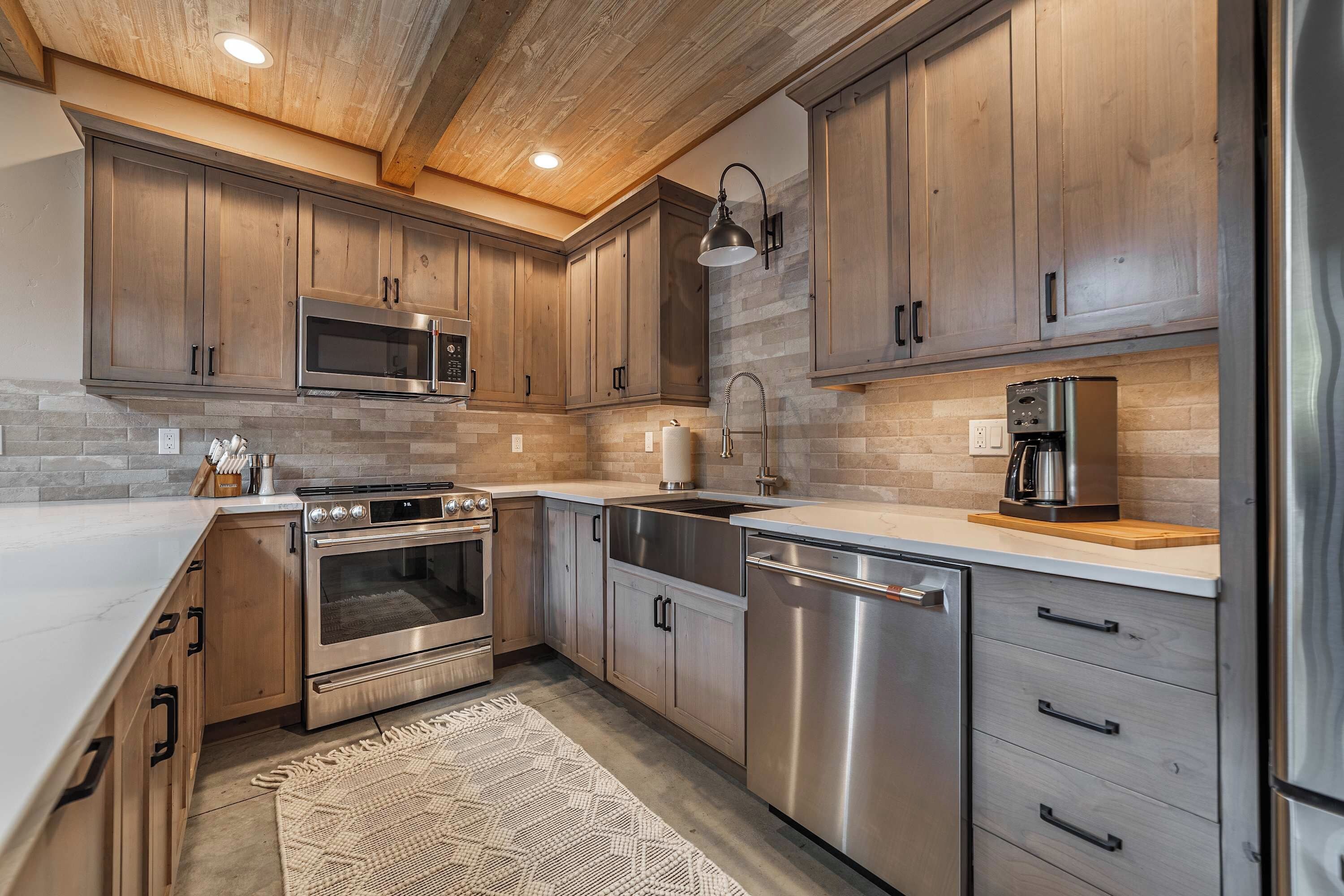 A modern kitchen with wooden cabinets, stainless steel appliances, and a stone backsplash.