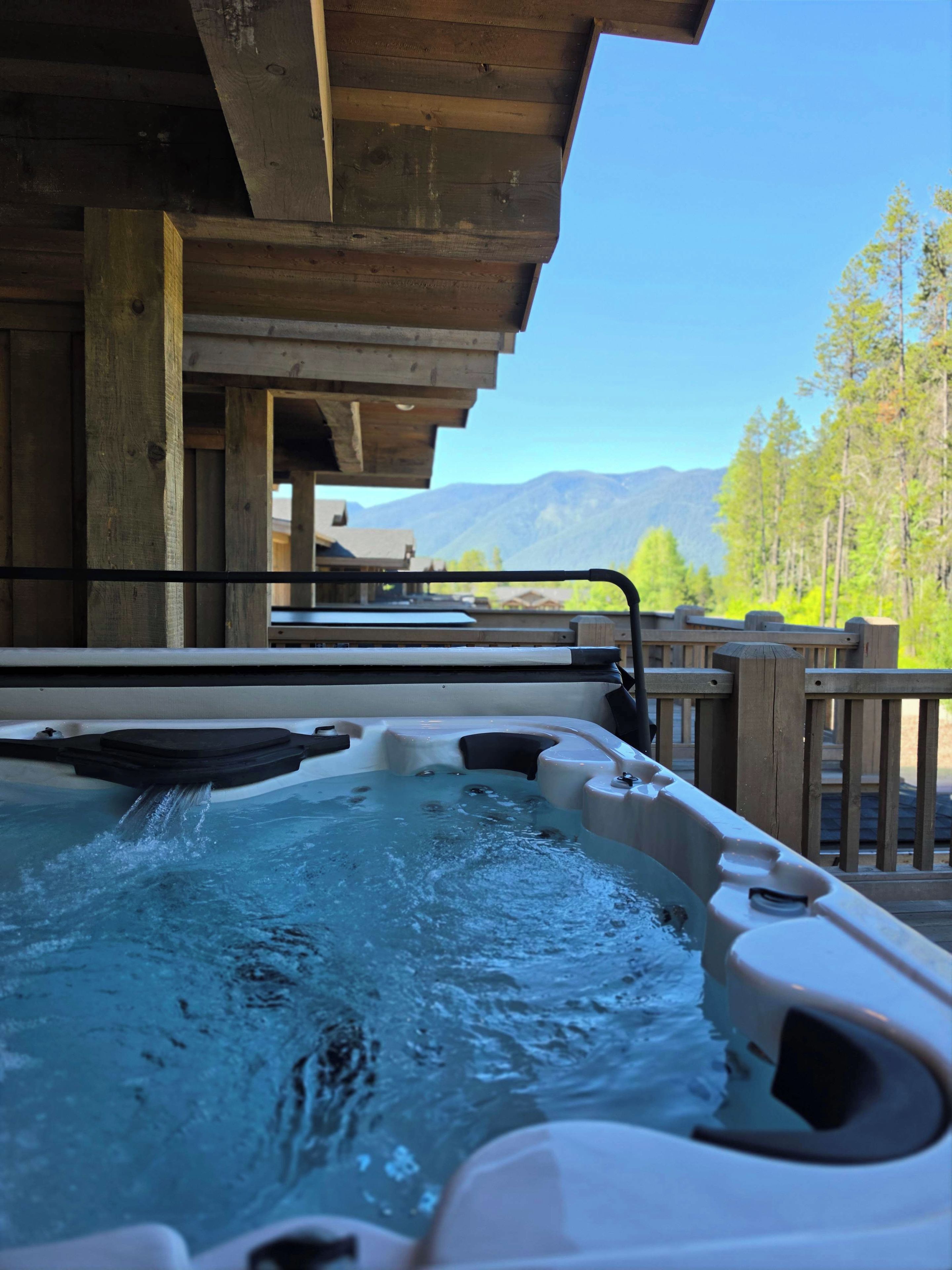 A hot tub with a wooden deck and a view of mountains.