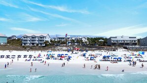 A beach with umbrellas, people, and buildings in the background. - 30A Ocean Pearl by Avantstay Newly Built Pool Access + Golf Cart Walk to Dune Allen Beach (Santa Rosa Beach)