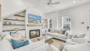 A living room with a fireplace, white sofas, and a ceiling fan.