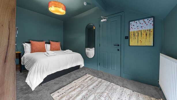 Ein Schlafzimmer mit einem Bett, einem Spiegel, einer Tür und einem Bild an der Wand.