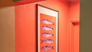 Ein Flur mit einem gerahmten Fischgemälde an einer roten Wand, einer Tür und einem Lichtschalter.