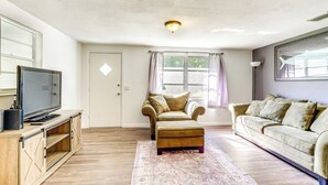 A living room with a television, two sofas, a coffee table, and a window with curtains.