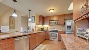 A kitchen with wooden cabinets, stainless steel appliances, granite countertops, and pendant lighting. - Lanai + Ocean Views: Secluded Holualoa Retreat! (Holualoa)