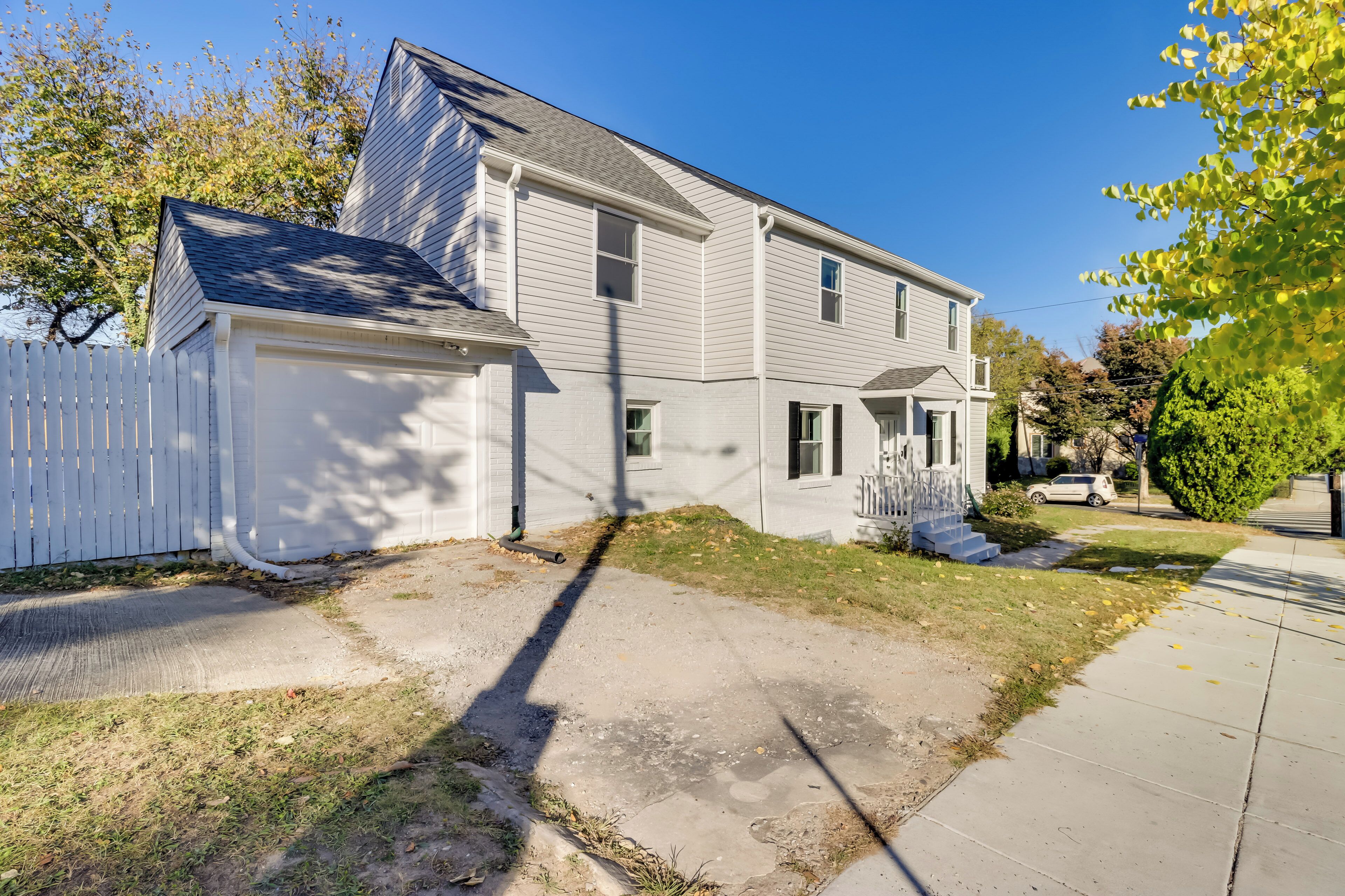 A two-story house with a garage, a front porch, and a driveway leading to the garage.