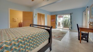 A bedroom with a bed, a ceiling fan, a wooden desk, and a view of the outdoors. - 8 Mi to Magic Sands Beach: Tranquil Home w/ Lanai! (Holualoa)