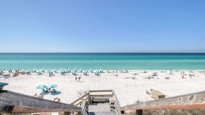 A beach with white sand, turquoise water, and blue umbrellas.