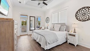 A bedroom with a bed, bedside tables, a ceiling fan, and a large window.