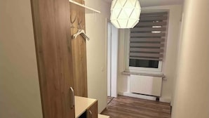 En smal hall med trägolv, en trägarderob och en hängande lampa.