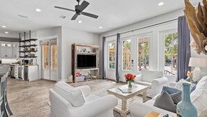 A spacious living area with white furniture, a wooden coffee table, and a television. - Totally Beachin by Avantstay Sleeps 18 Seacrest Beach (Panama City Beach)