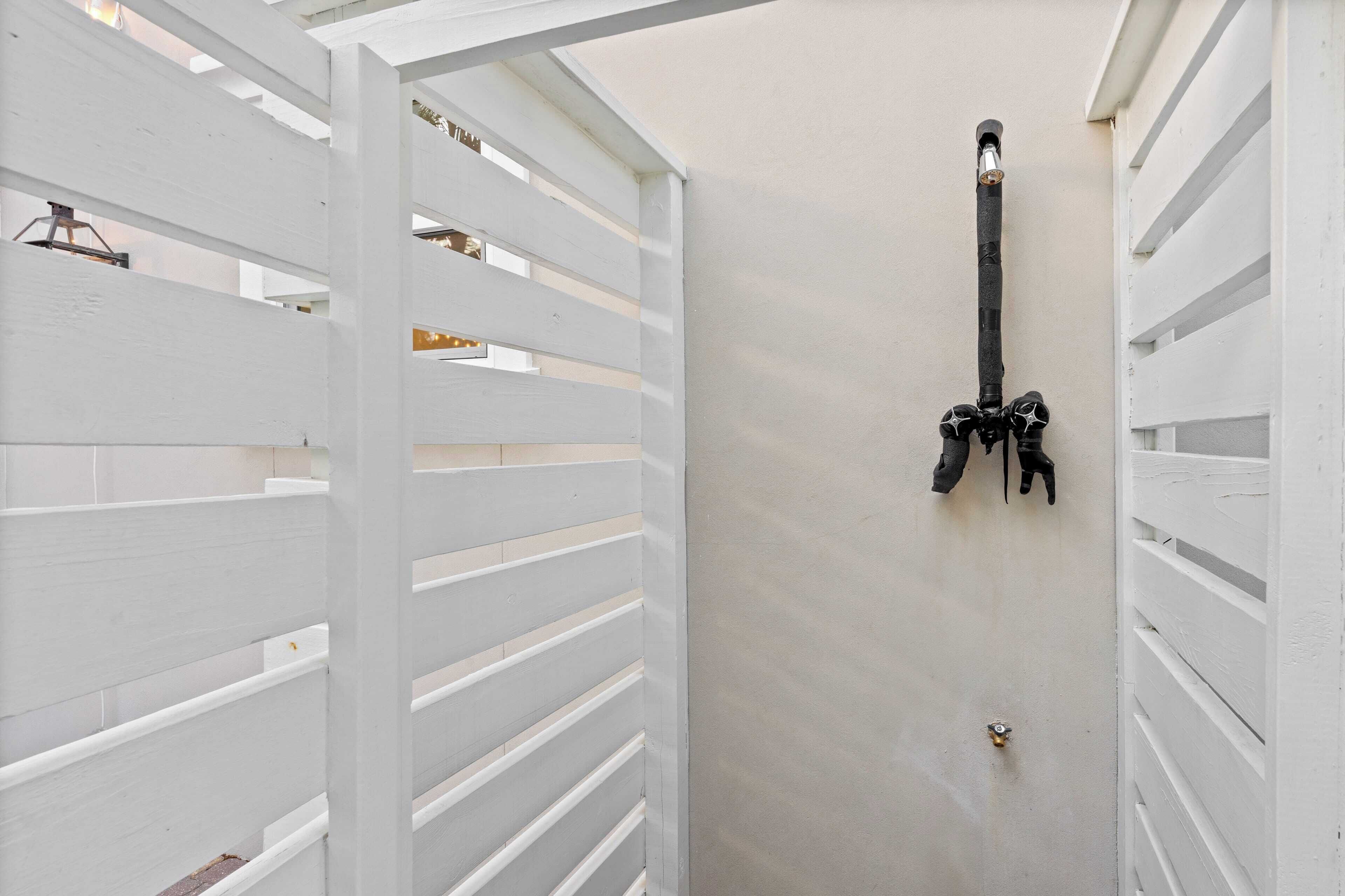 A white wooden structure with horizontal slats, a black metal fixture, and a small brass lock on a plain wall.