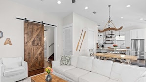 A modern living room with a white sofa, a wooden coffee table, and a sliding barn door. - Totally Beachin by Avantstay Sleeps 18 Seacrest Beach (Panama City Beach)