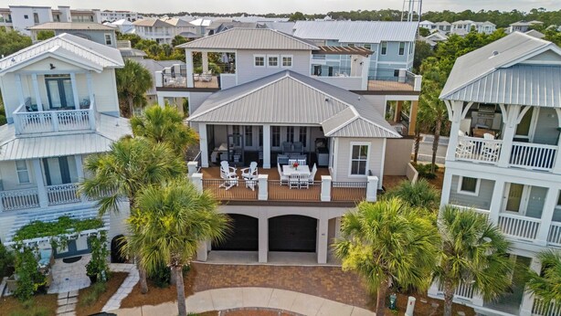 A coastal residential area with multiple houses featuring balconies and a central house with a patio and outdoor seating. - Totally Beachin by Avantstay Sleeps 18 Seacrest Beach (Panama City Beach)