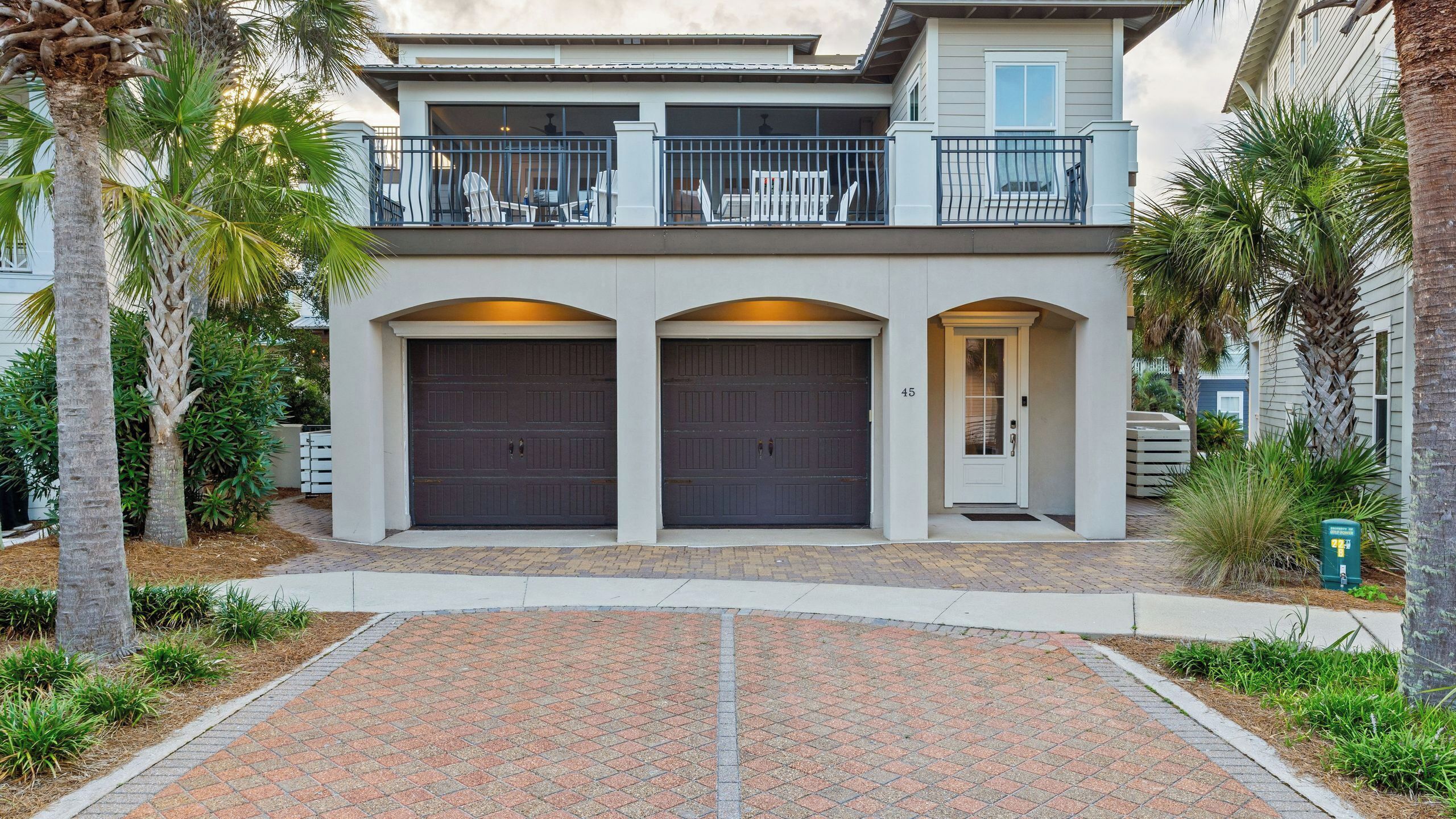 A two-story house with a covered patio, two garage doors, and a mailbox.