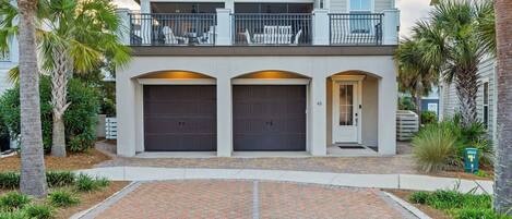 A two-story house with a covered patio, two garage doors, and a mailbox.
