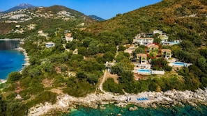 A coastal property with multiple buildings, a rocky shoreline, and clear blue waters.