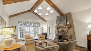 A spacious living room with a fireplace, comfortable seating, and a large window.