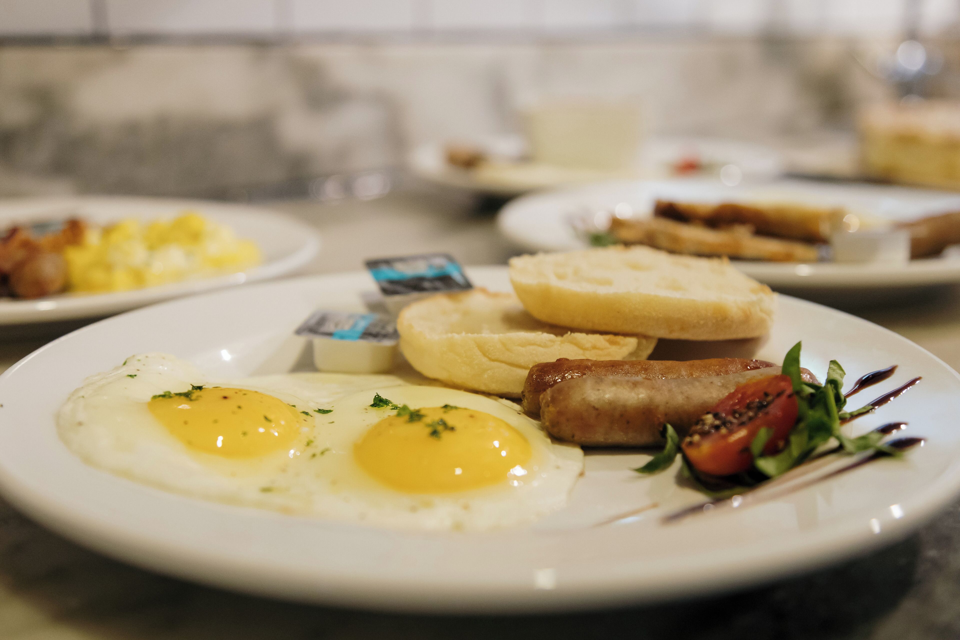 A breakfast plate with eggs, sausages, toast, and a tomato salad.
