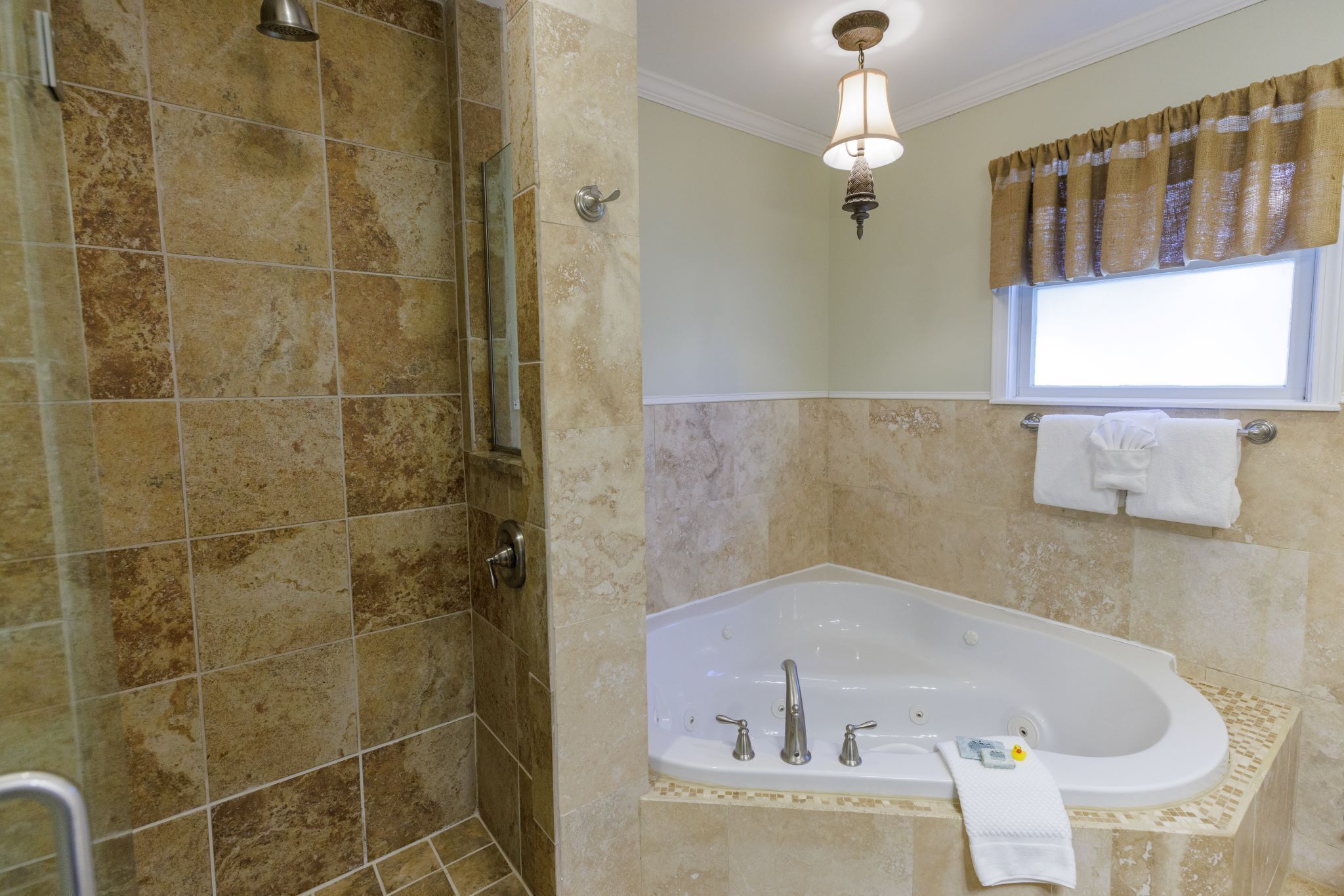 Un baño con bañera, ducha y ventana con cortina.